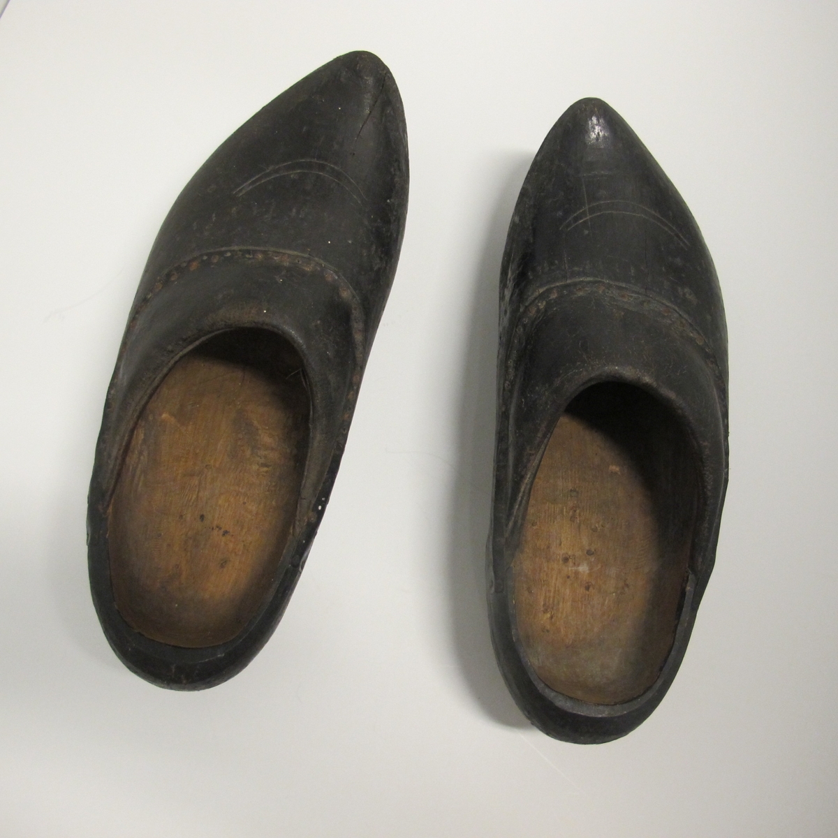 Skoene er sorte, med tre i bunn og i deler av kappen, der tuppen gå opp i en spiss foran. Den har noen innrissninger som ikke er tydet. Bare stykket nærmest vristen er av lær.
