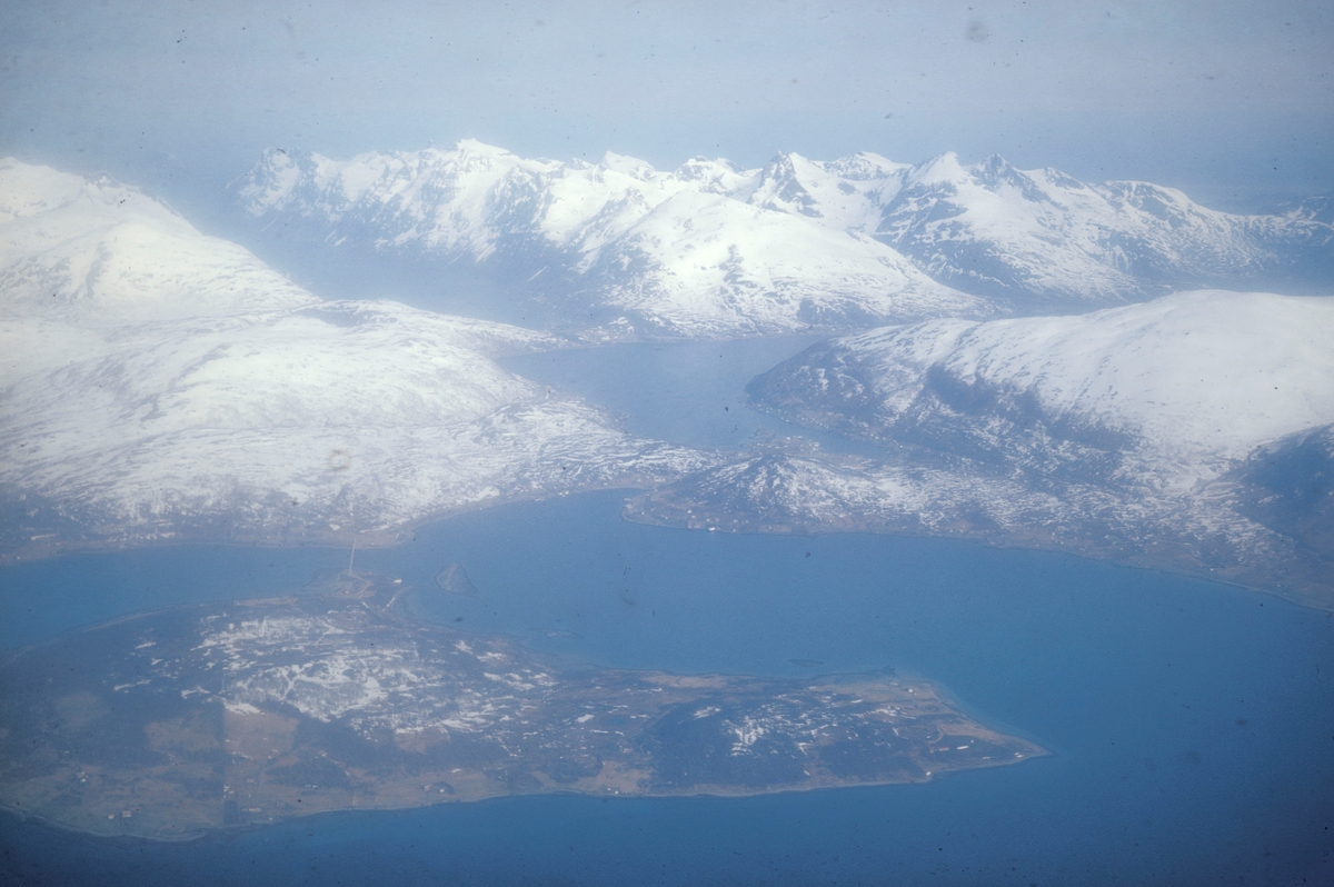 Flyfoto tatt fra sjøflyet til Einar Brun, professor i zoologi ved universitetet i Tromsø. Håkøya i forgrunnen og Kvaløya med Kaldfjorden i bakgrunnen.