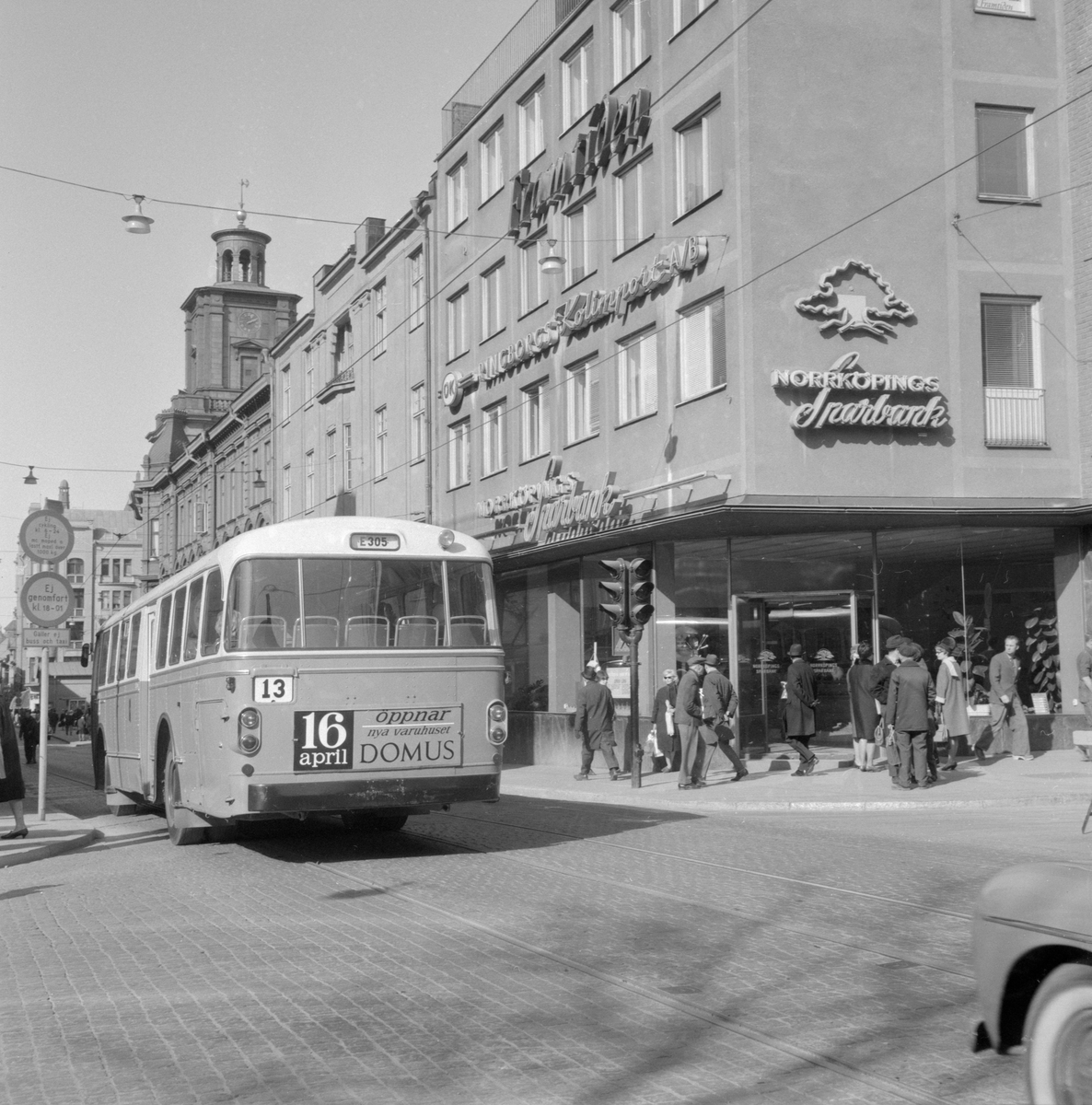 Ögonblick från Norrköping våren 1964. Vy längs Drottninggatan västerut från korsningen av Repslagaregatan. I fonden reser sig kampanilen till S:t Olai kyrka.