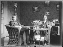 Mann og kvinne sittende ved bord i stue. Stuen er dekorert m