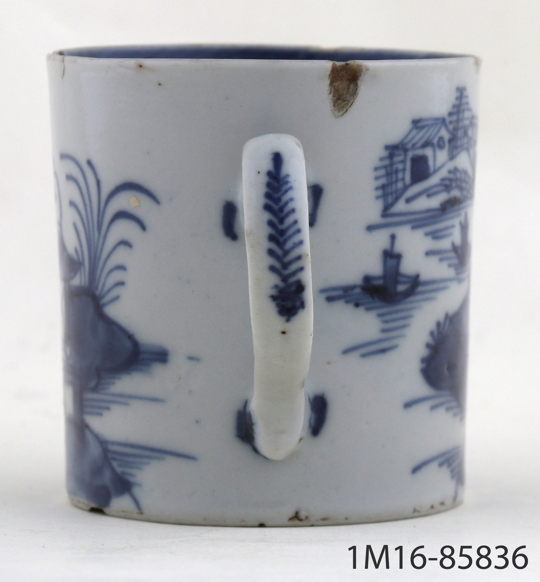Mugg av vitt kinesiskt porslin. Dekorerad med pagodlandskap i blått. Med handtag.