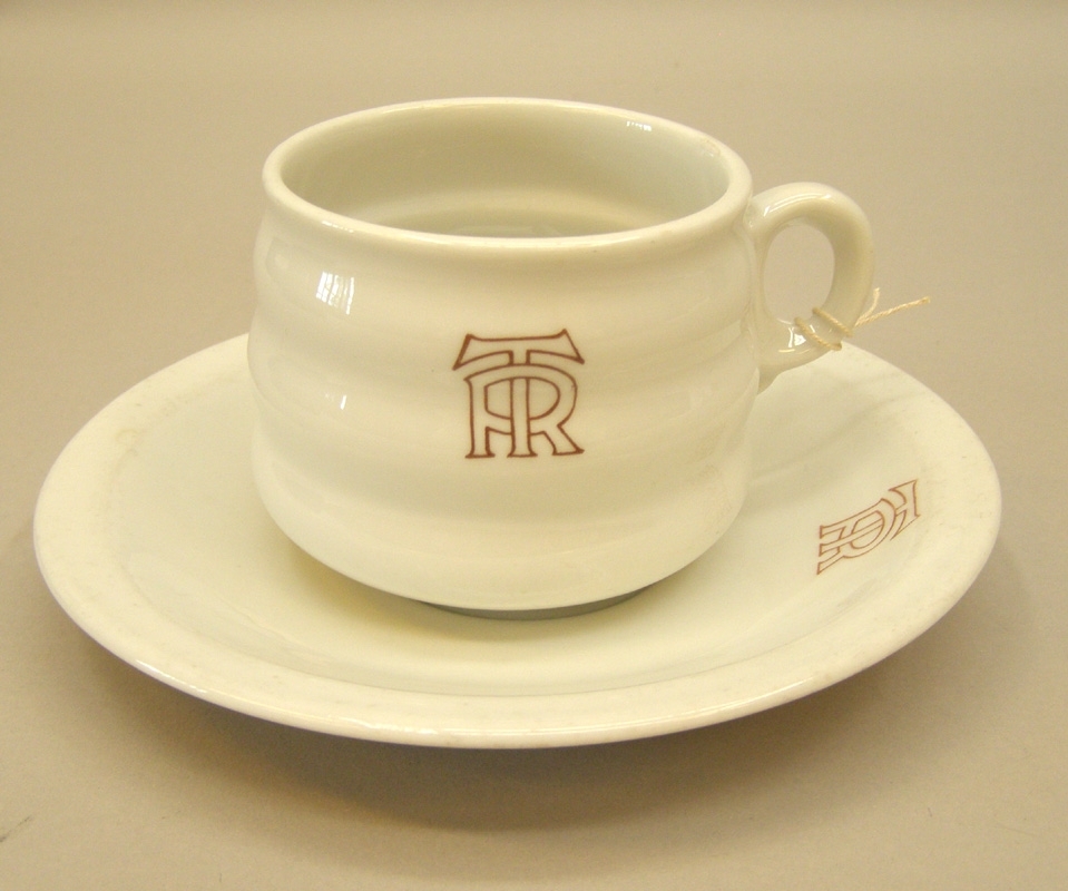 Vit kaffekopp av porslin med två "midjor", märkt i brunrött med "TR"= Trafikrestauranger. Koppen kallas "Beckeböljakoppen" på grund av sin utformning.
Med tillhörande fat.