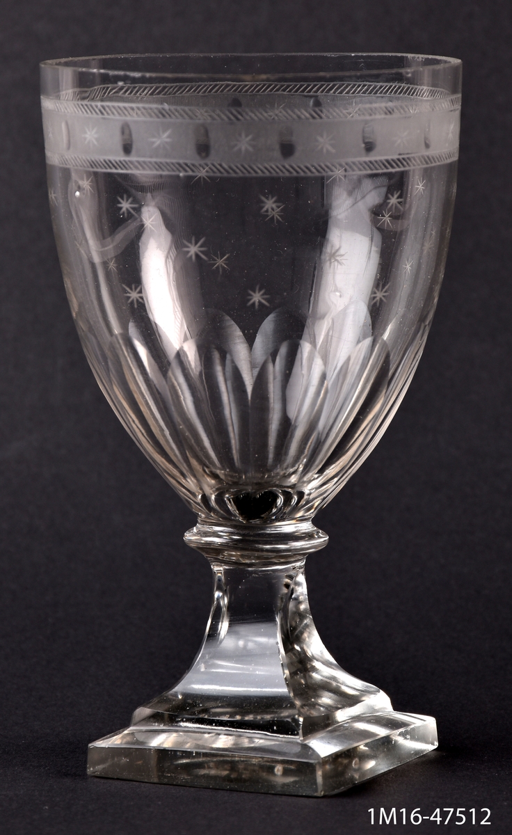Ölglas, med fyrsidig fot, slipat och etsat, upptill en bård med stjärnor och små ovaler, längre ned stjärnor.