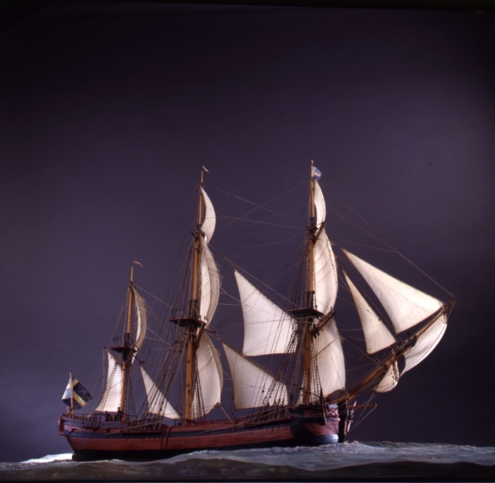 Modell av kattskeppet BARON ANDERS von HÖPKEN efter ritningar av Fredrik Henrik af Chapman daterade 1758. 6 sjömansfigurer (av bly) på däck. Monterad på sjöplatta av skulpterat trä.