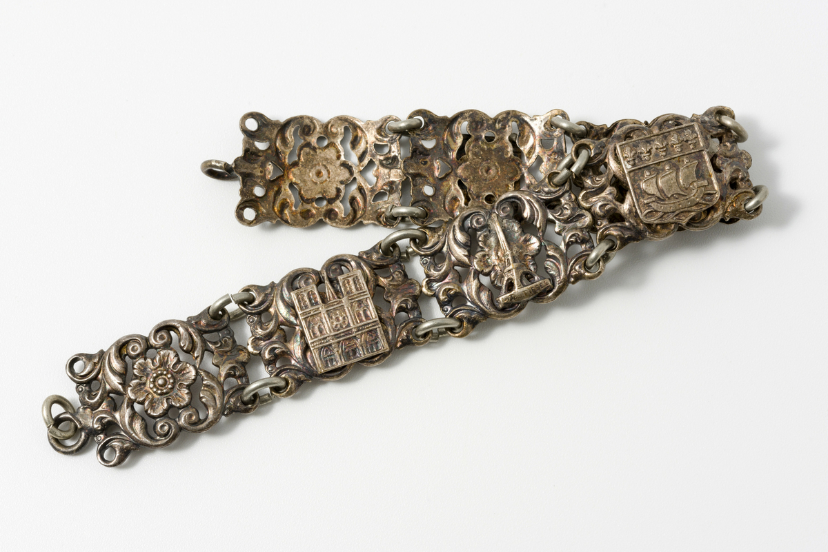 Armbånd i metall dekorert med motiv av blomster og kulturminner/landemerker (f.eks. eiffeltårnet og triumfbuen)