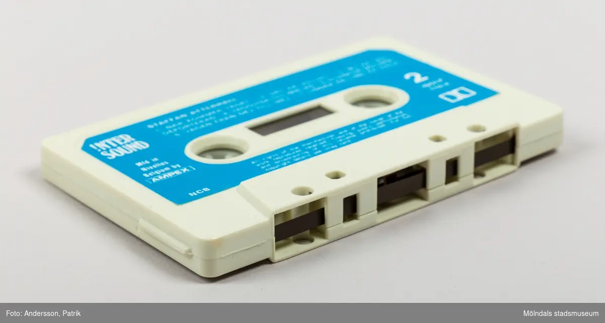 Ett kassettställ av hårdplast för förvaring av kassettband. Stället har en rund fot med manuell snurrfunktion. Kasettställets form är kvadratisk och färgen är röd. Ställets invändiga sidor är ljusgula. Hörnen har en vertikal sida med plast i träimitation. Kassettstället innehåller plats för 20 kassetter. I detta ställ finns 8 kassetter. På ställets ovansida finns en något upphöjd svart cirkel. Inuti cirkelns mitt finns en guldfärgad text med namnet Audio master.
Kassettband introducerades på marknaden 1963 av det nederländska teknikföretaget Philips. De användes för att spela in musik och talinspelningar. Kassettbanden var väldigt populära mellan 1975-1995.