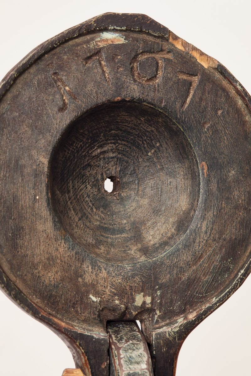 Kruset er lagget og grønnmalt. Sju gjorder, tre oppe og fire nede. Utskårne akantusranker på kruset, og andre rankedekkorasjoner på håndtaket. På innsida av lokket er det skåret inn 1767, under botnen innsvidd eierens stempel.
