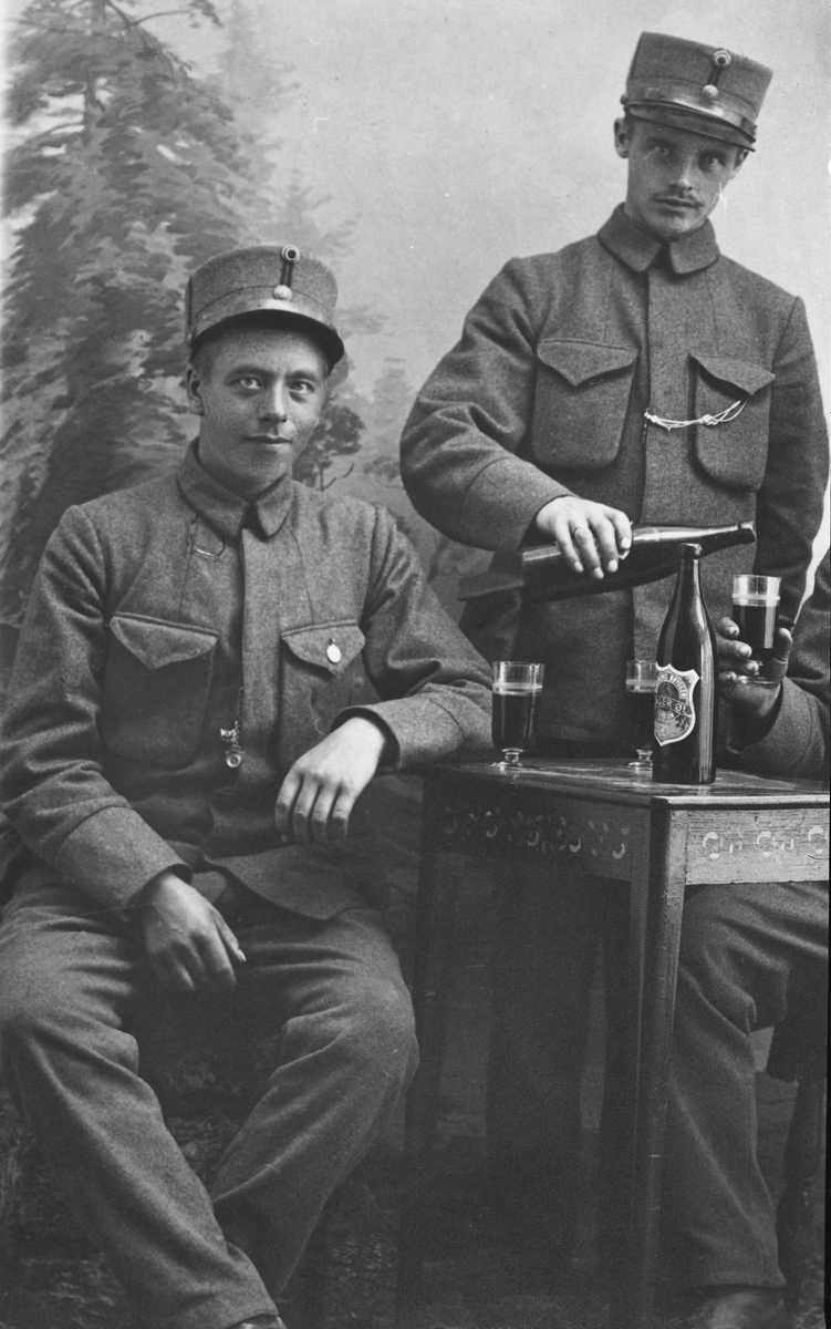 Portrett av tre unge menn i uniform som tar seg en øl - nærbilde av