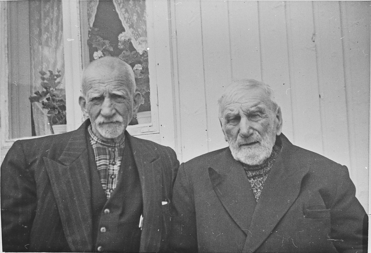 Ola Nevramoen og Martin Flaget ved husveggen i Setra på Grenskogen, 1955.