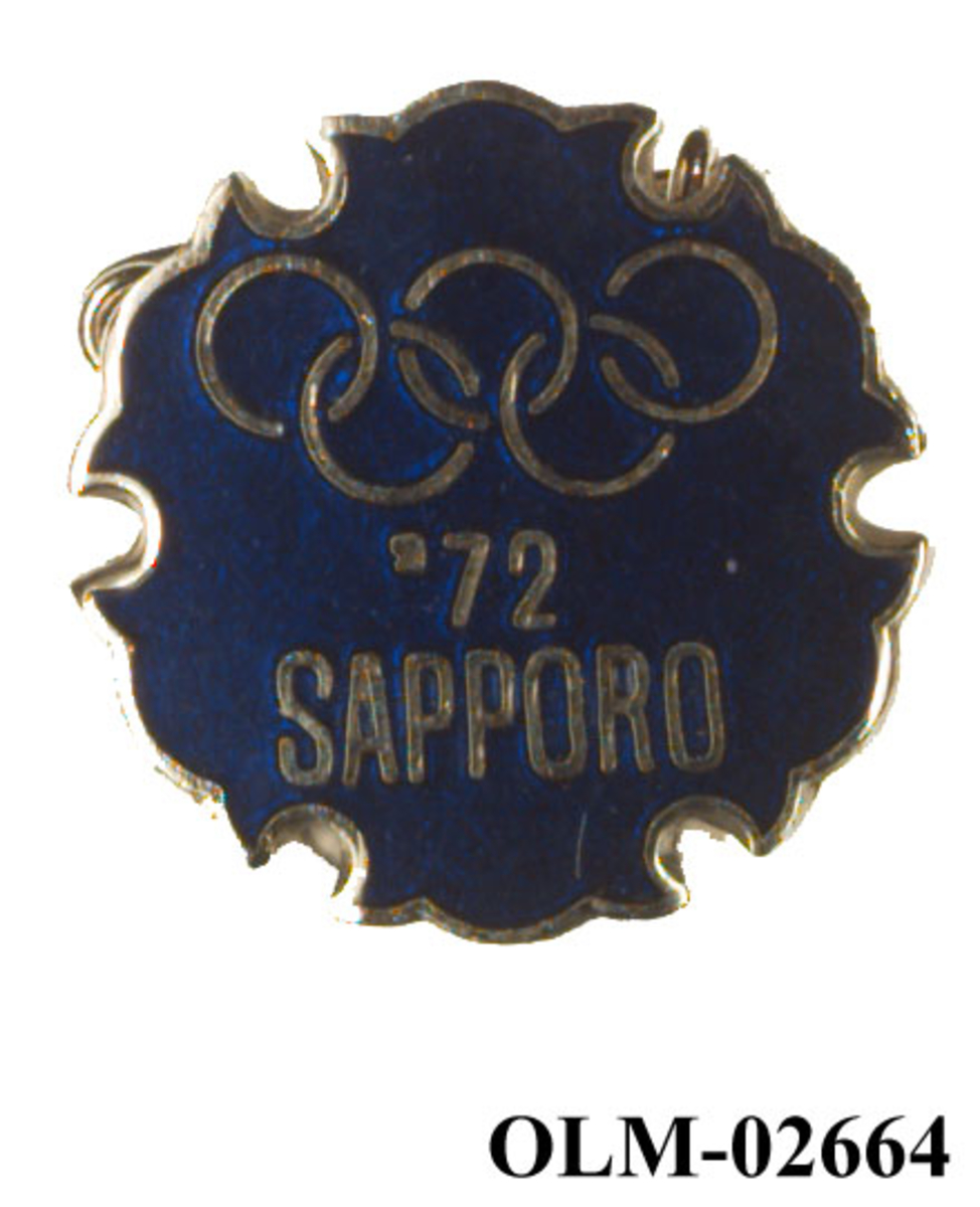 Tilnærmet rund pins med motiv av de olympiske ringene.