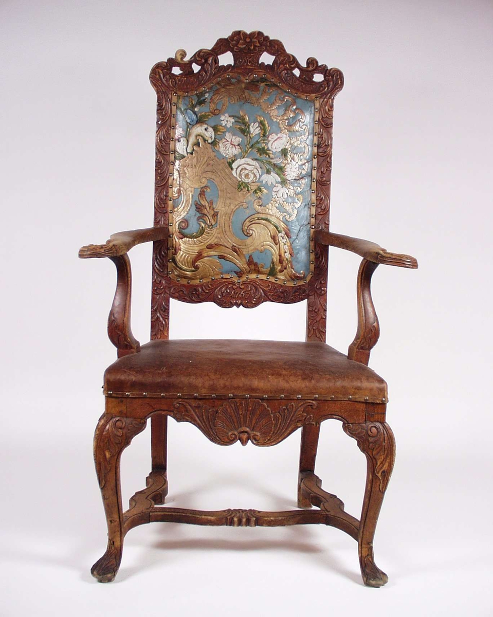 Armstol i umalt bøk og bjørk med skinntrukket rygg og sete. Ryggen har gyldenlær. Utskjæringer på rygg, armlener, sarg og bein. På ryggen er det skrevet NK og 1757. 