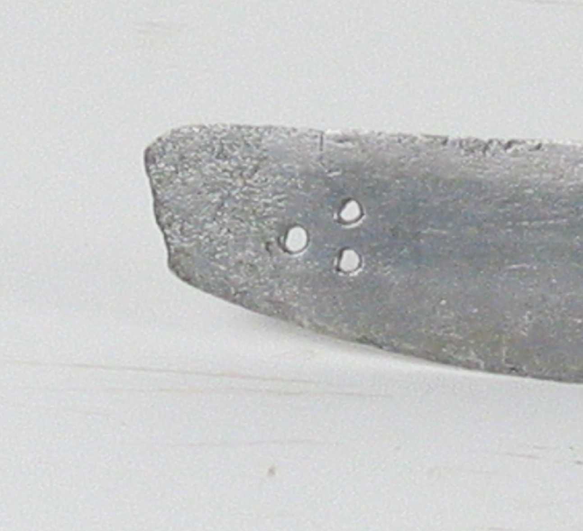 Pyramideformet knapp med kryssfilt dekor og asymmetrisk feste med 3 sidebøyler med fortykninger på midten på utsiden og en på innsiden. Nyreformet parerplate på utsiden og klingebrekker og tommelbøyle på innsiden. S-formede, runde parérstenger med fortykning med filt dekor og dråpeformet avslutning.
Tregrep. Enegget krum, kileformet klinge med en ryggstillt blodrand. Ryggslipt mot spissen. Spiss brukket. Tre hull på spiss. Ett smedstempel.

