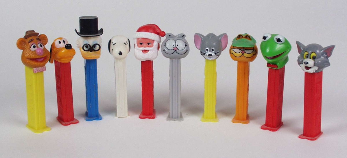 Ti pastilldispensere i plast der lokket er hodet til kjente tegnefilmfigurer: Snoopy, Pusur, Langbein og Kermit.