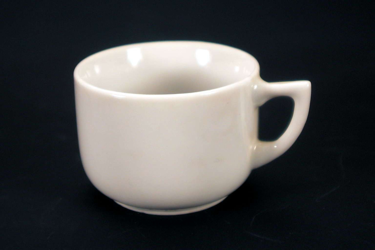 Liten, hvit kopp uten dekor. Den er stemplet 'Made in Japan', sammen med et merke med bokstavene OTO (eller OTC). 