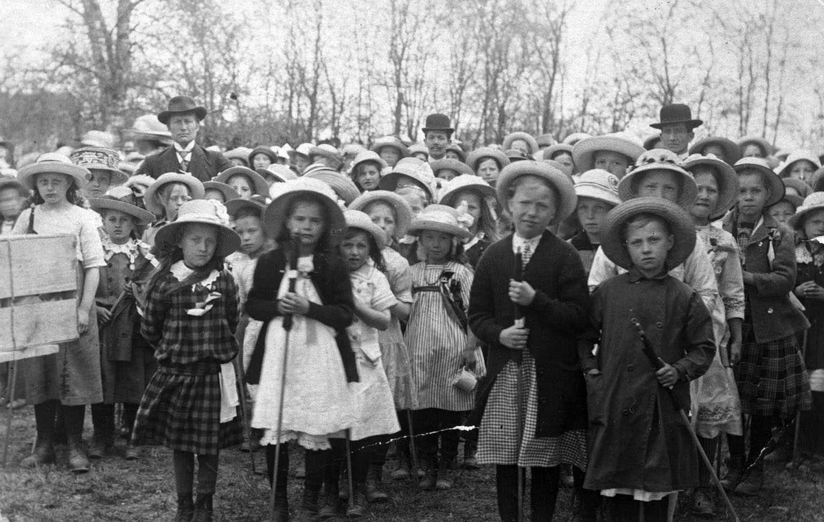 17. maifeiring Skedsmo 1914. En flokk med festkledde barn, bare jenter? Tre voksne menn har hodet over flokken.
