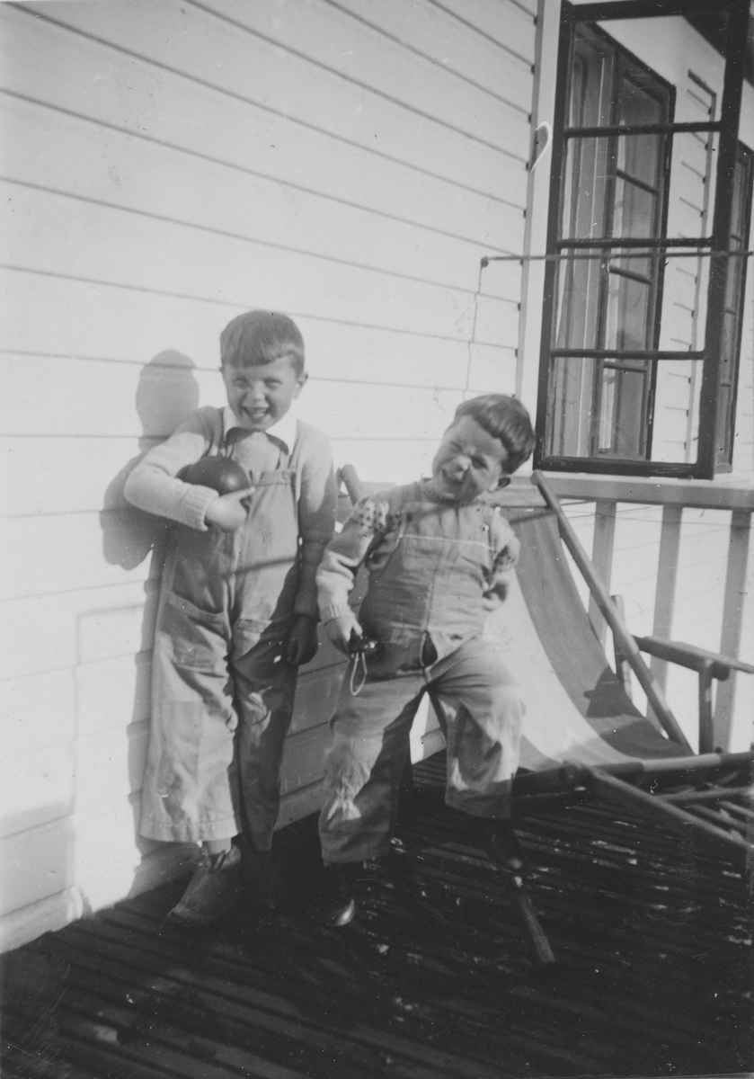 To små gutter på verandaen med leker og en fluktstol
