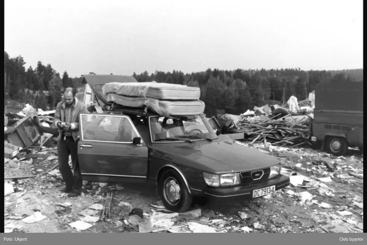Mann ved overlesset bil (Saab) på søppelfylling.
