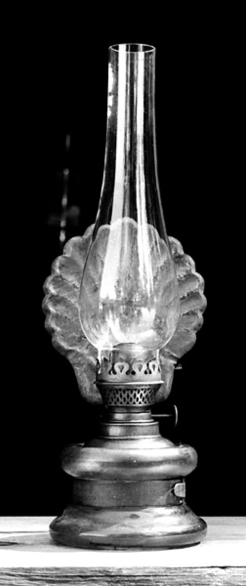 Den hører til utstyret fra Kvanstrandkoia fra Trysil, som står på Prestøya. 
Lampa er ei bordlampe. Glasset er fra Hadeland Glassverk. 
På den ene sida har lampa en blikkskjerm som er utformet som et blad. 
Lampa er en flatbrenner (flat veke). 
