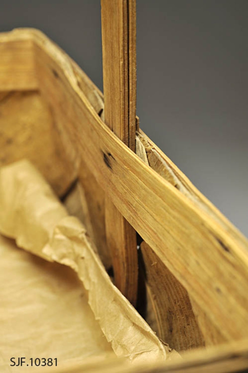 Sponkurven er skråflettet, og har en bøyd hank. Sponene er jevnbrede, og er maskinhøvlet.

Bunnen har en rektangulær form. Sponene er vikt opp, og sidene er rette. 
Kanten danner en form tilsvarende bunnen. På kanten er det lagt på et smalere spon på hver side som er festet med metallstift. 

Innvendig og utvendig skjøt ligger på hver sin kortside.
Hanken ligger på innsiden av de flettede sidene, og er festet mellom flettet side og indre kantspon. Hanken består av et tykkere spon som delvis er kløyvd i to. Spiker og stifter i kurvkant er rustne.

Kurven har tydlige spor etter jordslag. 

Det ligger et dobbelt gråpapir i bunnen på kurven.
