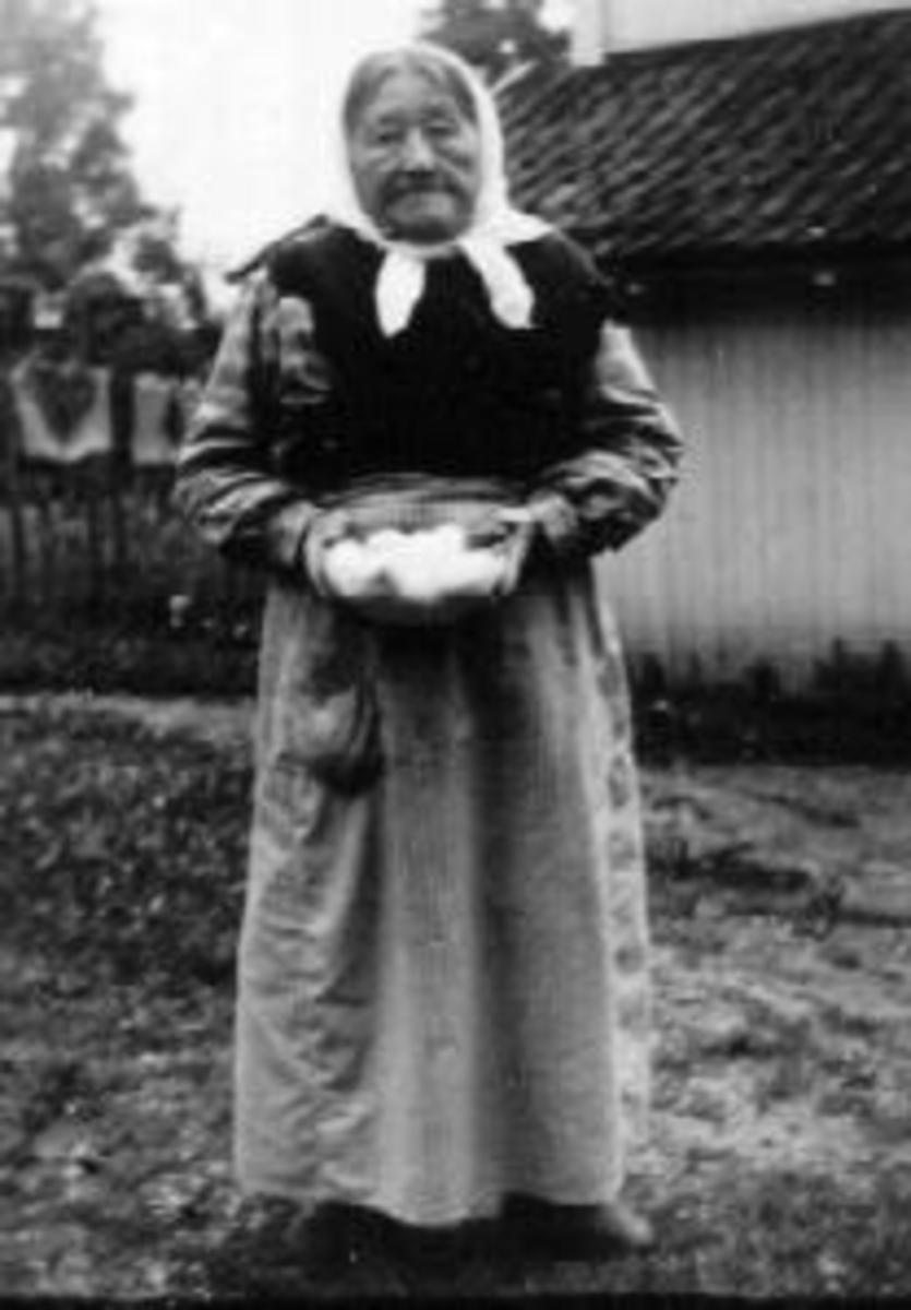 Portrett av Oline Dæhlie (1860-1946) den eldre. Hun holder en glassbolle med egg. Datter av Eli (1824-1900) og Hans Dæhlie (1820-1898). Hun bodde på Dæhli, Nes, Hedmark som føderaadskone sammen med sin søster Karen (1855-1947).