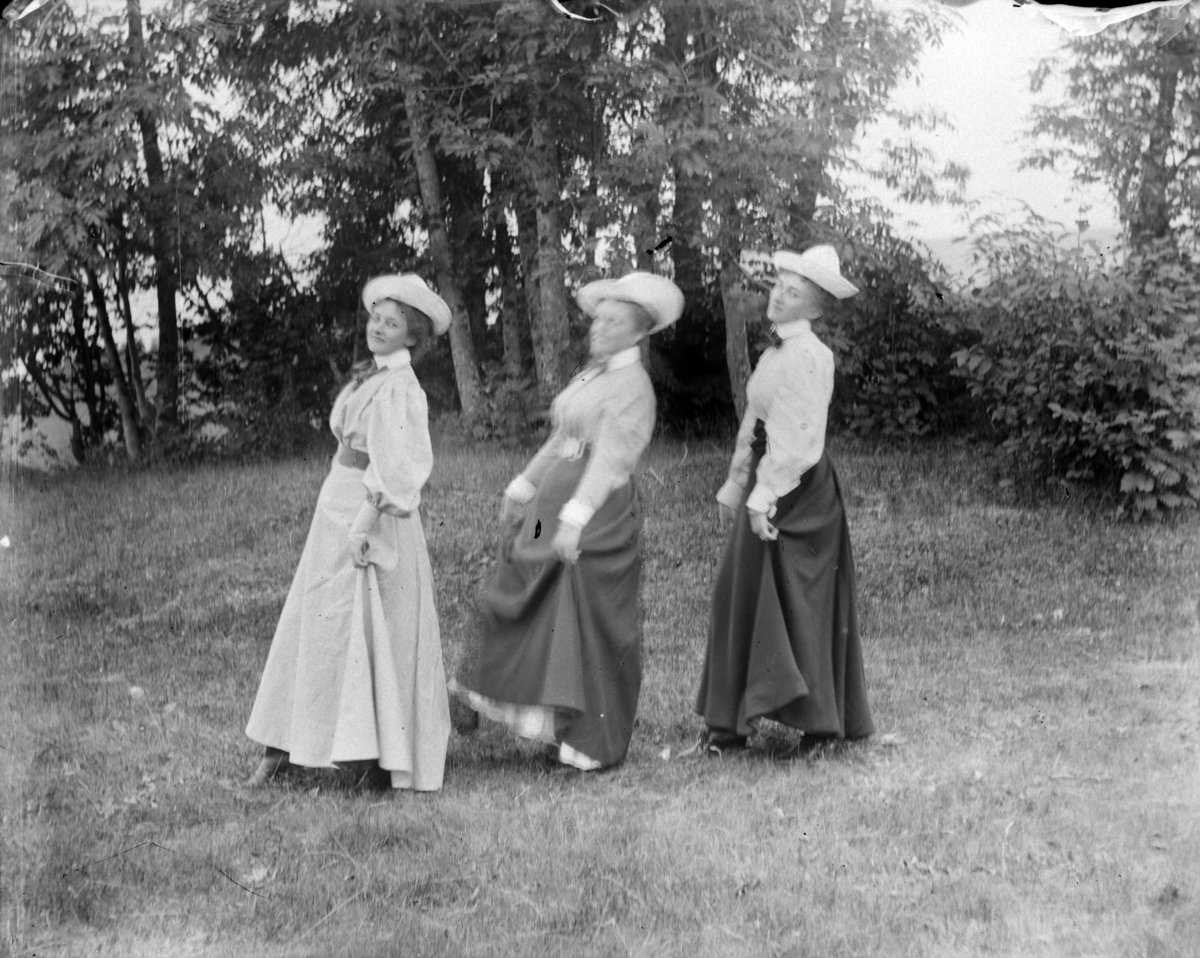 Tre kvinner med hvite hatter i en hage. Lol Misen (f. Mellbye) t. v. 