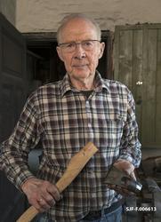 Smeden Oddbjørn Knudsen, fotografert med ei nysmidd merkeøks