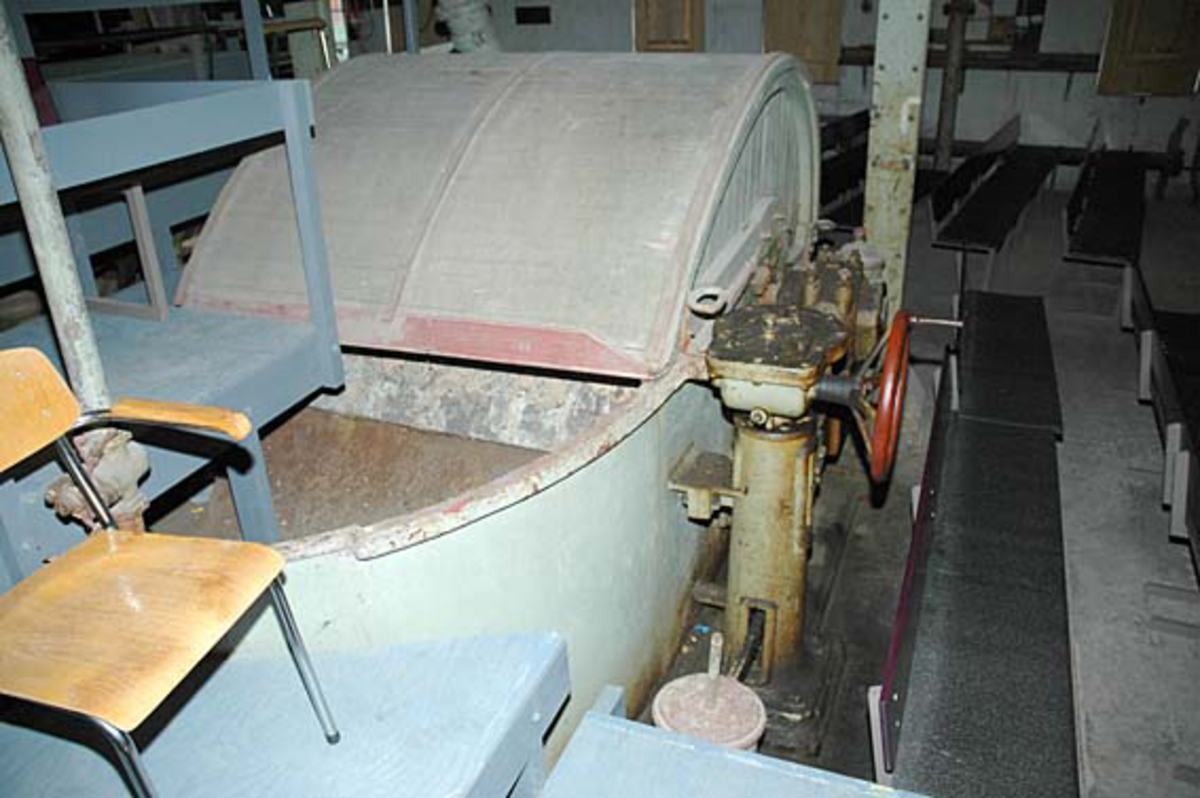 Hollenderen ved Klevfos Cellulose- & Papirfabrikk i Løten i Hedmark.  Denne maskinen ble levert av Drammens Jernstøperi i 1910 og installert i forbindelse med at Klevfos-fabrikken ble gjenoppbygd etter brannen høsten 1909.  

Hollenderen ble altså brukt til å blande og male papirmassen i.  Det dreier seg om et digert kar med en innvendig midtvegg, samt en valse (såkalt «kubbe») og et «grunnverk».  Ytterflatene på de roterende hollenderkubbene var besatt med skinner eller «kniver» av stål eller fosforbronse.  Disse maler mot det faststående grunnverket, som også har kniver av samme materiale.  Trykket kubben skulle ha mot grunnverket bestemte malegraden på papirmassen.  Dette trykket kunne justeres ved hjelp av det rødmalte rattet til høyre i bildet.  Malingsgraden (fibrilldannelsen) hadde stor betydning for papirkvaliteten.  

Det blåmalte amfiet og stålrørstolen i forgrunnen står på dette stedet fordi at hollenderiet etter at Klevfos-fabrikken ble museum har vært brukt som teatersal for forestillingen «Arbesdaer».  Også benkene vi skimter til høyre i bakgrunnen er satt hit for å skaffe sitteplasser for publikummet til denne forestillingen. Ådalsbruk.