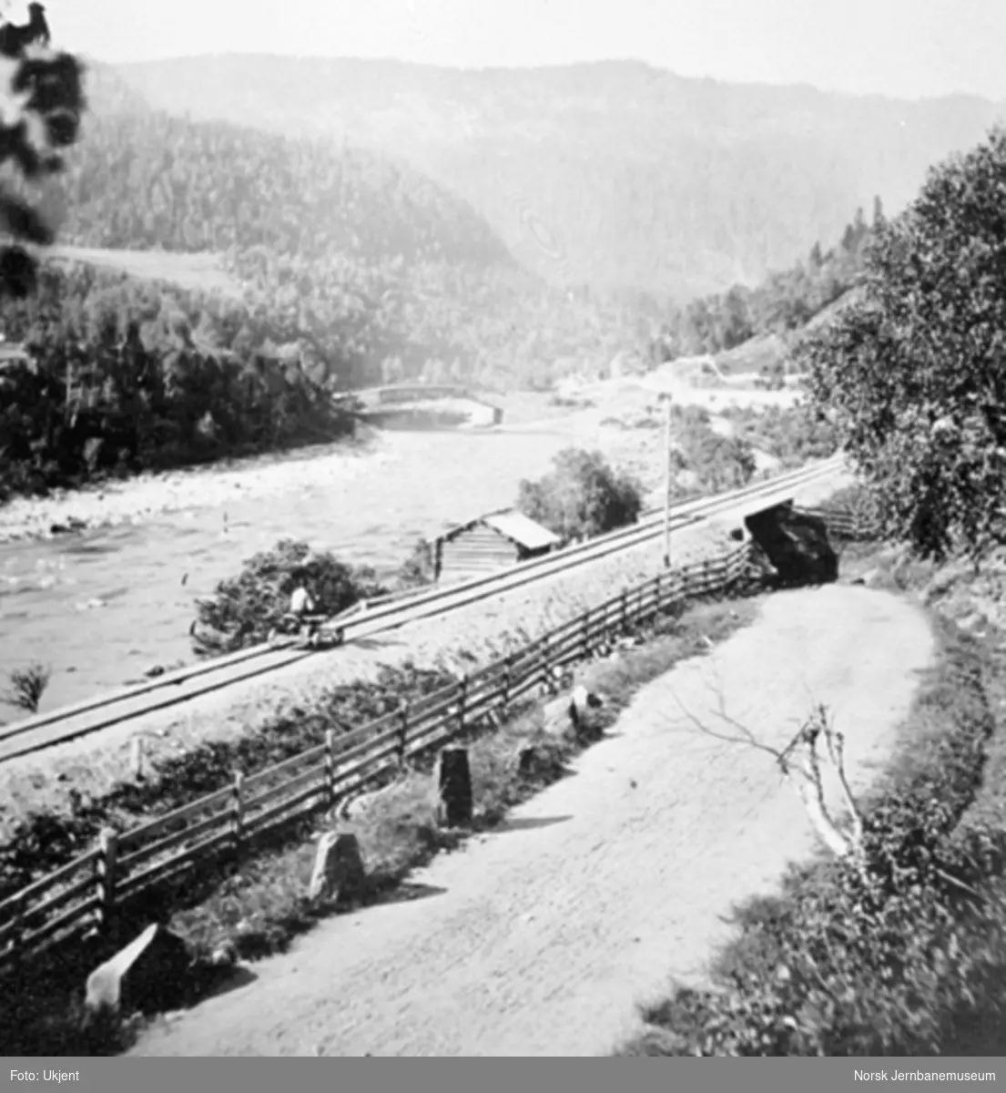 Jernbanelinjen med landevegen ned Fjeset-bakken, en vegundergang og Osøy bru i bakgrunnen
