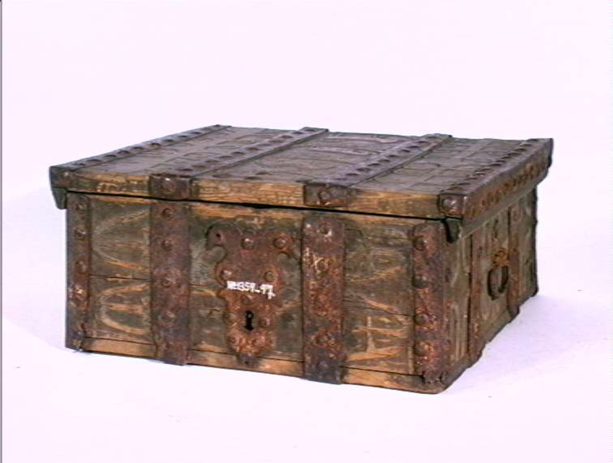 Skrin med flat lokk, jernbeslag og utskåret dekor med plante- og dyrmotiv.
