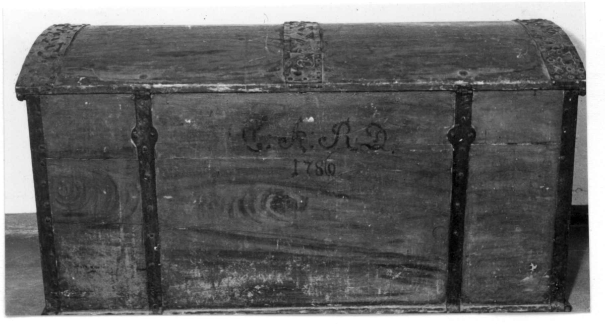 Kiste med buet lokk og gjennombrudte jernbeslag og bånd. Utvendig ådret og med initialer og årstall på baksiden. Innvendig bemalt med to engler og små hus i lokket.