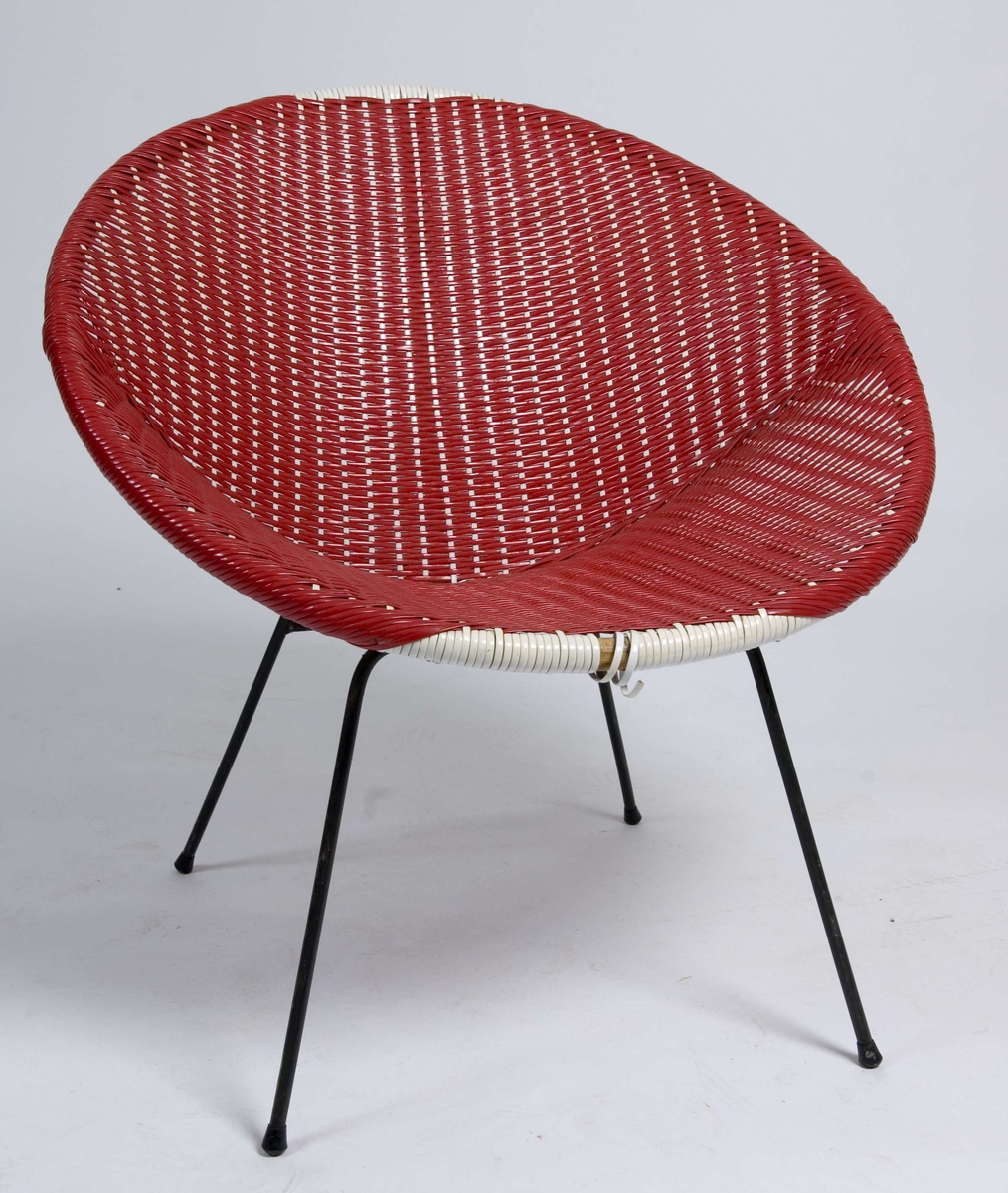 Rund stol med rammeverk av bambus, trekk av rød og hvit plastfletting. Fire tynne bein av stålbolt.
