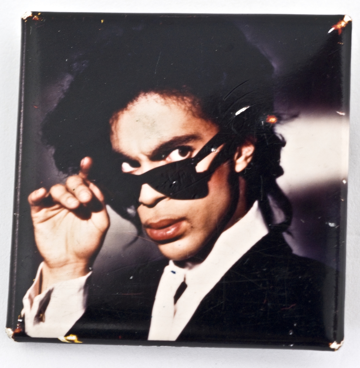 Kvadratisk buttons med portrett av Prince.


