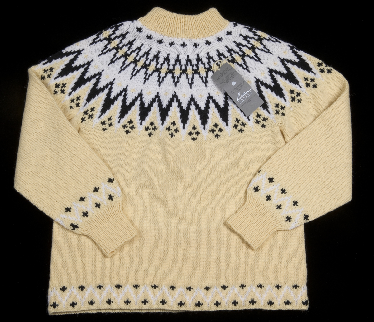 Gul strikket genser med mønster i hvit og svart.
