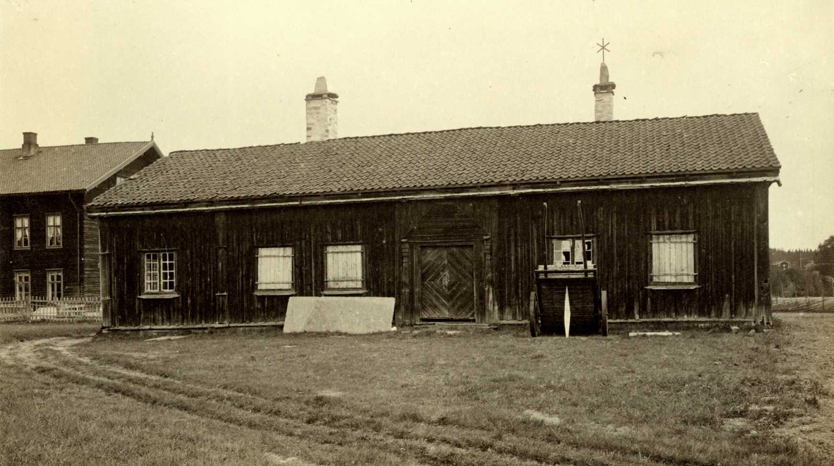 Petershagen (Grindhagen), Elverum, Sør-Østerdal, Hedmark. Bygd ca. 1770. Lav stue med  lemmer for vinduene, sett mot inngangsdøra. Annet hus bak og hestekjerrre foran. Nå på Glomdalsmuseet.