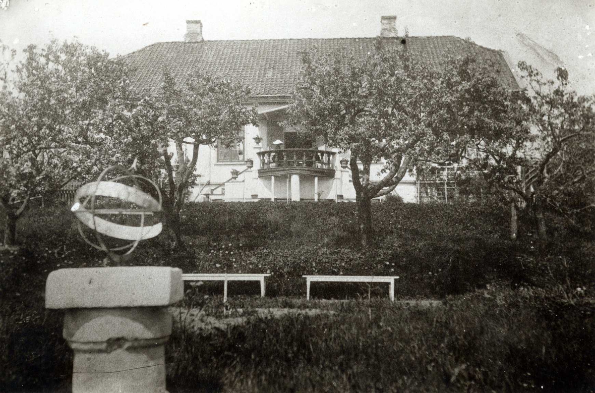 Linløkken, Skrivergården, Eidsvoll, Øvre Romerike, Akershus. Hvitt trehus med veranda bak frukttrær og hekk. Solur.