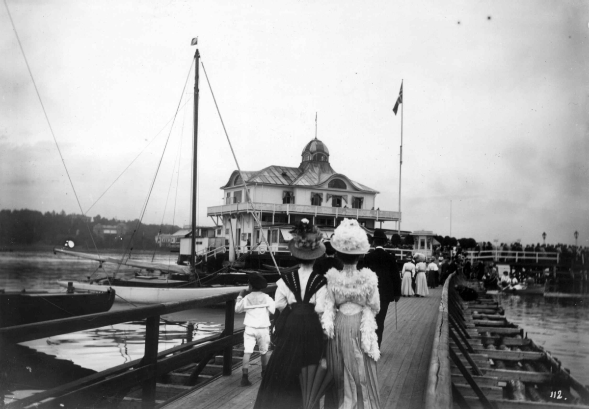 Bygdøy, Oslo 1908.  Dronningen restaurant. Mennesker på brua til Dronningen.  Kvinner i lange kjoler og med hatter.