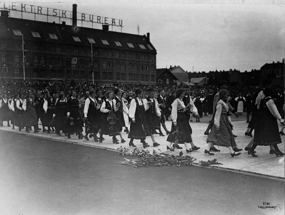 Folkedansstevne på Frogner Stadion 1925.
Prosesjon. Bybebyggelse i bakgrunnen.