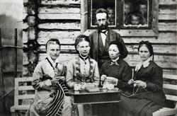 Gruppe, foran laftet husvegg, Kviteseid. 4 kvinner hekler og