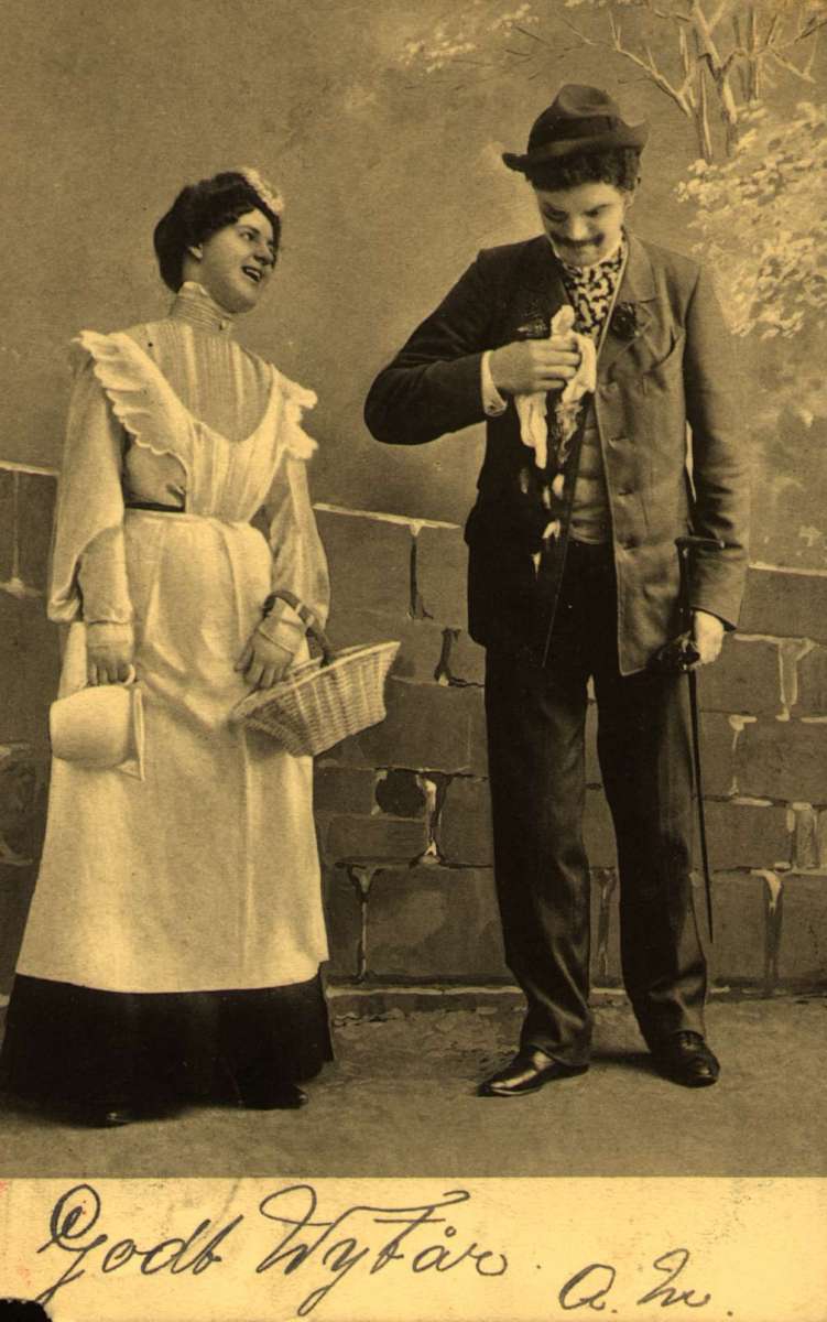Postkort. Nyttårshilsen. En mann og en kvinne i munter samtale.  Antakelig en scene fra en revy eller et teaterstykke. Stemplet 30.12.1904.