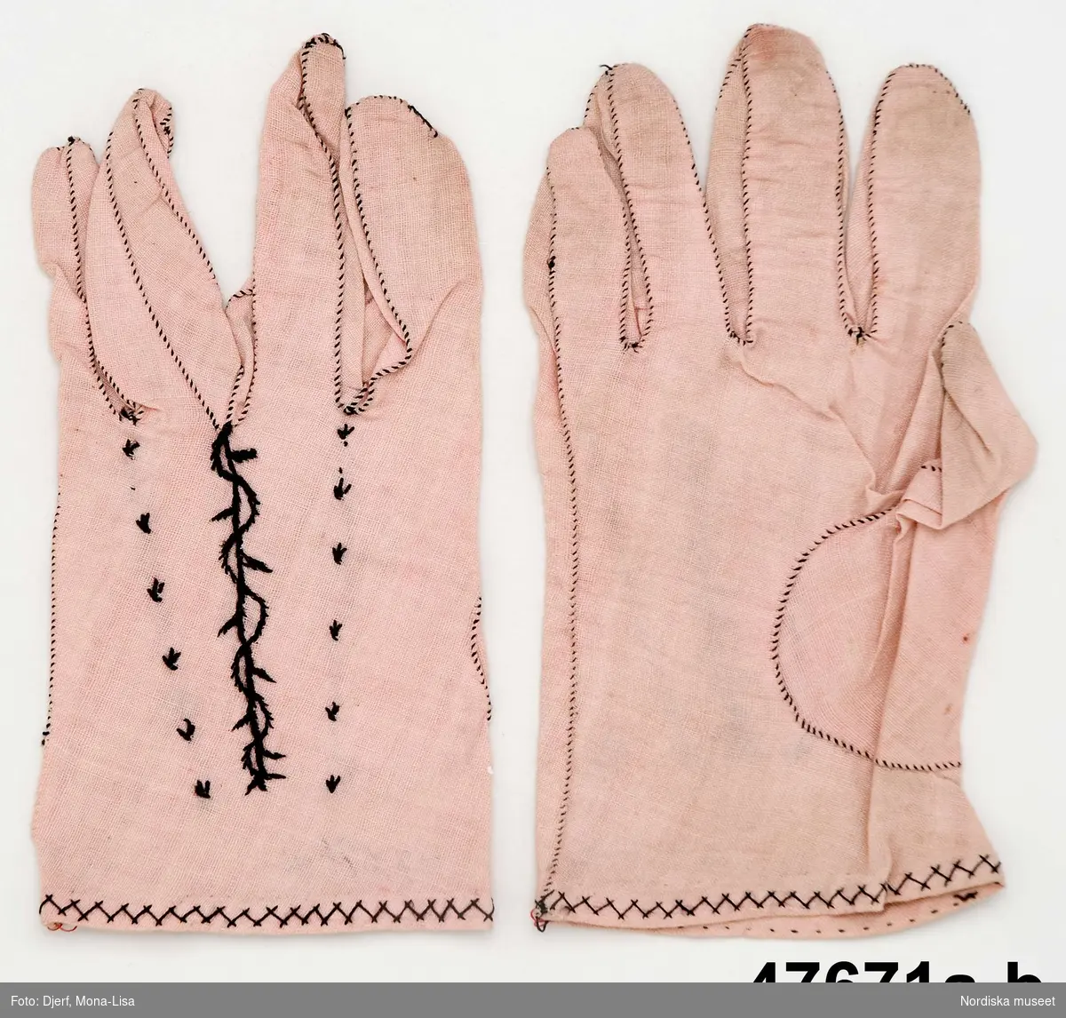 1 par fingervantar sydda för hand av rosa  bomullslärft , som skurits på skrå.  På handens ovansida 3 prydnadssömmar sydda med svart  silke i flätsöm och stjälksöm. 
 Jfr med likadana sydda i siden inv.nr 47672
 Använda som brudvantar.
 /Berit Eldvik 2013-04-18