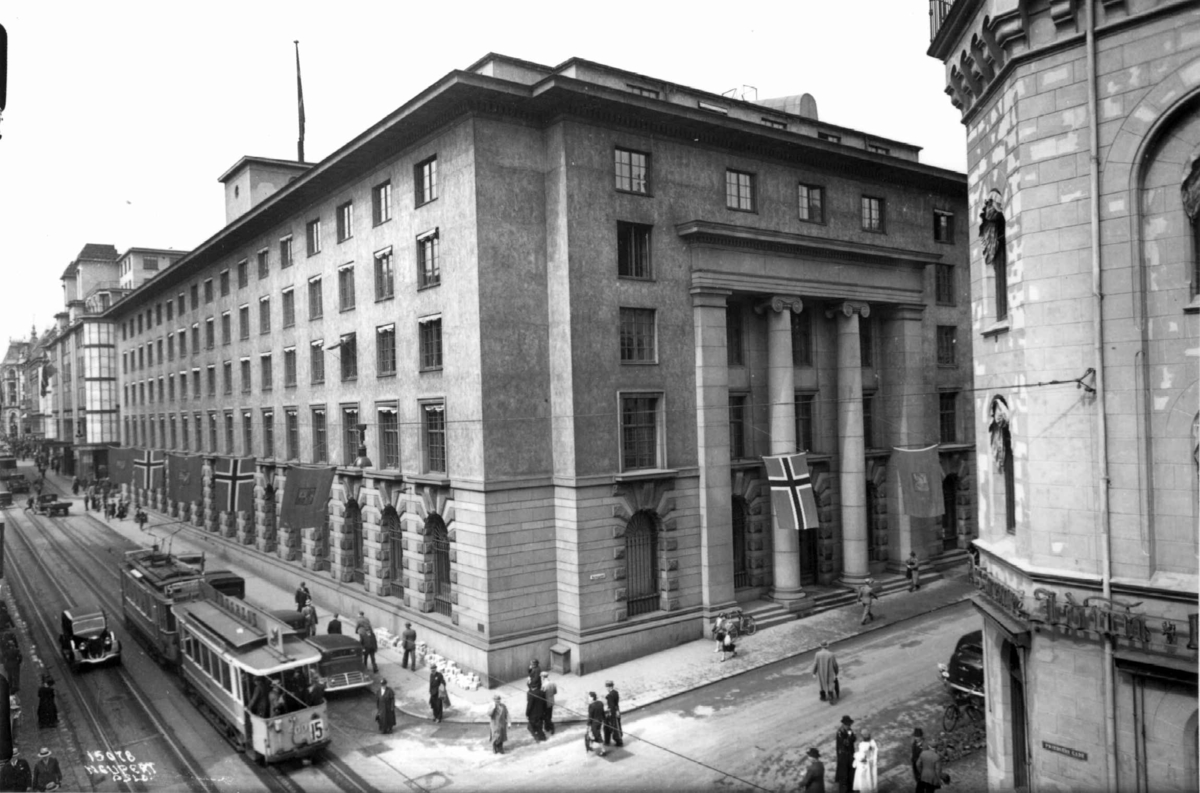 Den Norske Creditbank, Kirkegata 21, Oslo. 1936. Gatebilde med trafikk og bygningen.
Trikk, biler og fotgjengere.
