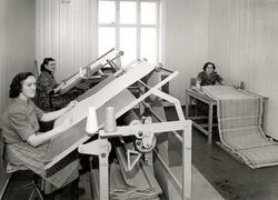 Tre kvinner arbeider med tekstil ved arbeidsbord på Gjøvik V