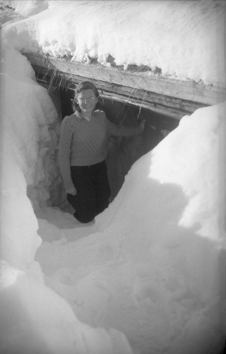 Kari Arentz ved inngangen til det nedsnødde feriestedet Ligardshaugen i Nordbygda, Eggedal. Fotografert påsken 1951.