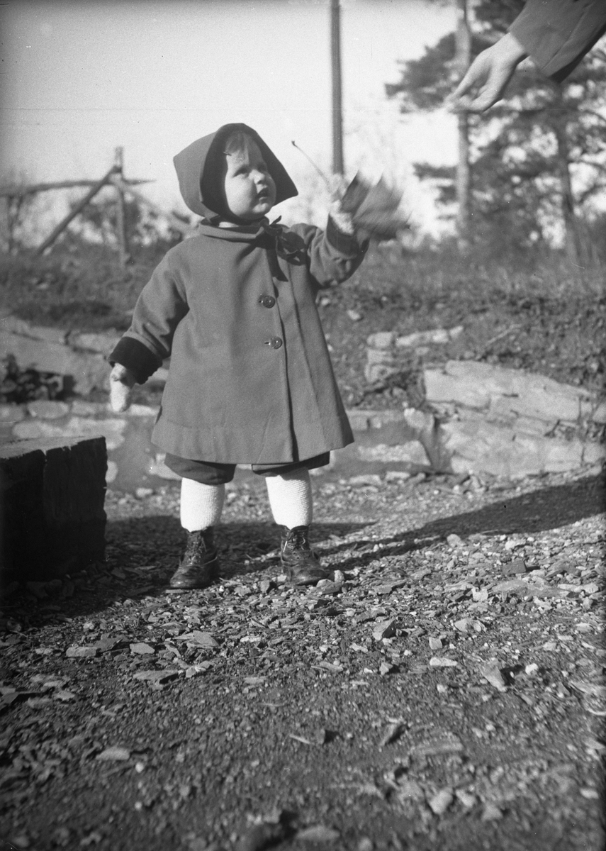 Guri Arentz står i hagen med ny kåpe. Fotografert oktober 1930.