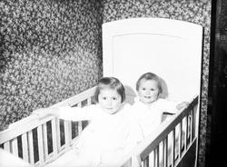 Søstrene Guri og Siri Arentz sitter sammen i en seng. Fotogr