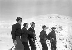 Fem personer med snødekte fjell i bakgrunnen. Holmenkollrenn
