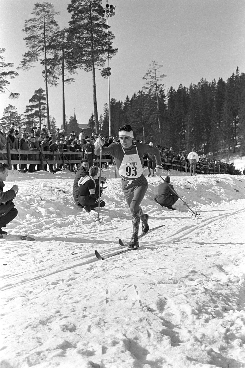 Skiløper med startnummer 93 i Holmenkollen. Publikum langs løypa.  Pressefotografer på sidelinjen. Holmenkollrennene 1963.