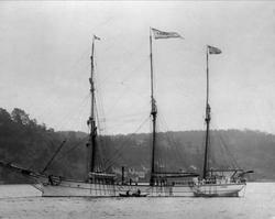 Seilskuta "Vardvik" ligger oppankret. Småbåt ved siden.