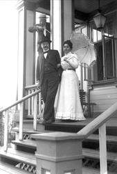 Par gående ned fra veranda, mann som skyter på dem med lekeg