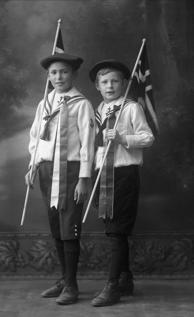 Gruppeportrett, to gutter i matrosdrakt med norske flagg og sixpence. Edgar og Nicolay Martin.